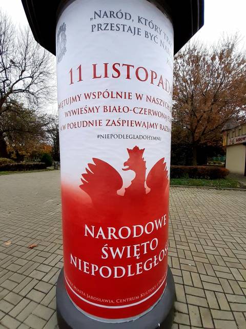 Słup ogłoszeniowy z okolicznościową grafiką z okazji 11 listopada.