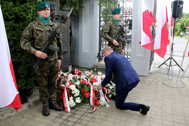 Zastępca burmistrza Dariusz Tracz podczas składania wiązanki kwiatów pod pamiątkową tablicą.