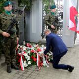 Zastępca burmistrza Dariusz Tracz podczas składania wiązanki kwiatów pod pamiątkową tablicą.