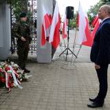 Zastępca burmistrza Dariusz Tracz podczas składania wiązanki kwiatów pod pamiątkową tablicą.